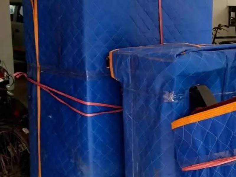 Tall furniture piece secured with padded moving blankets and heavy-duty straps