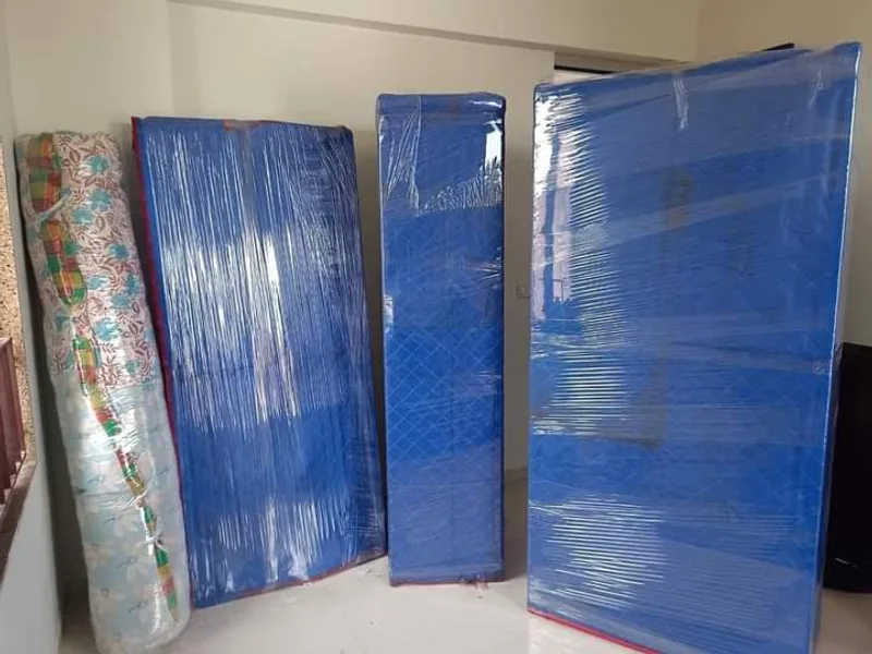 Bed mattresses sealed in protective wrap alongside rolled carpet in bubble film