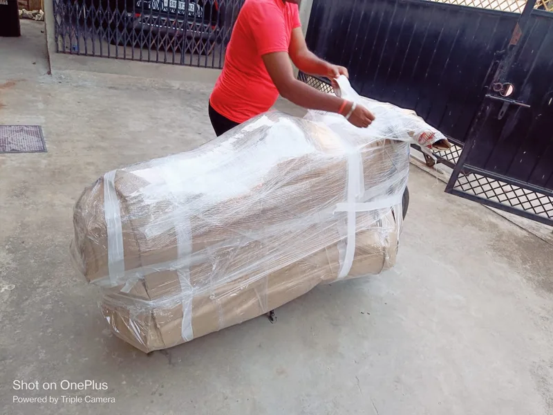 Mover wrapping living room sofa in corrugated cushioning and stretch wrap outdoors
