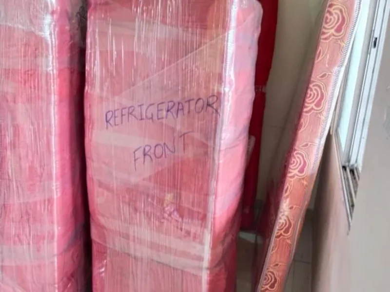 Home refrigerator clearly tagged and wrapped alongside bed mattress in bedroom