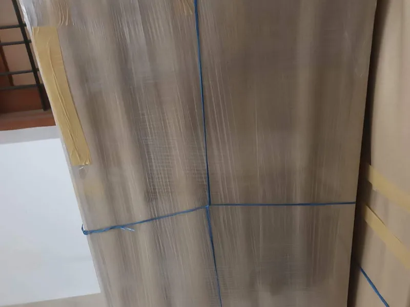 Double-door wooden wardrobe wrapped in protective padding standing indoors