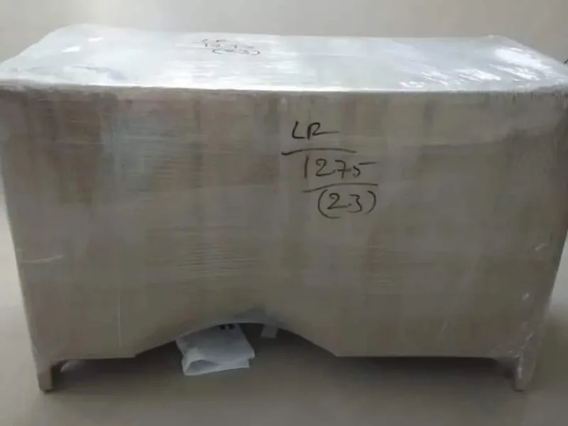 Washing machine appliance wrapped in white stretch wrap with consignment label