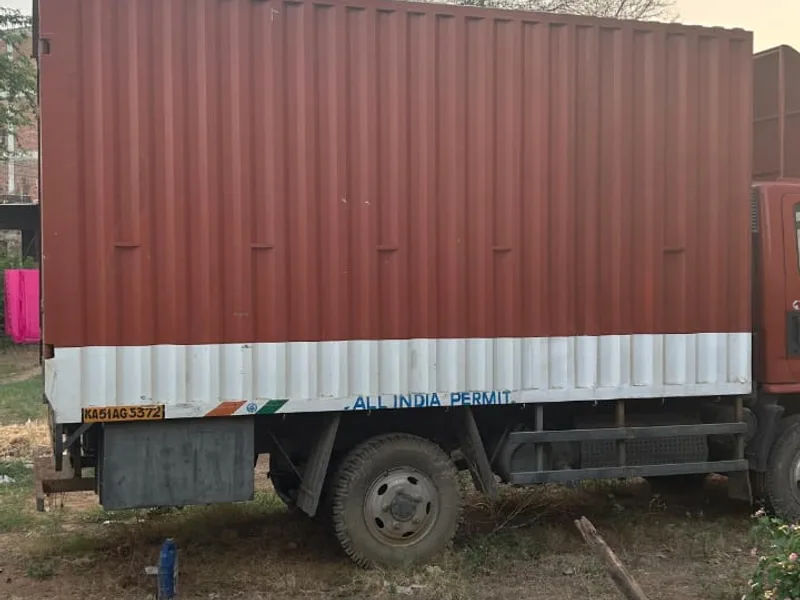Red closed-body container logistics truck positioned for cargo dispatch